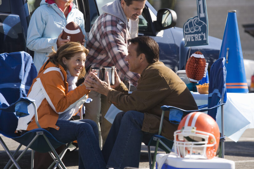 Fans gather at a tailgate party before a football game.