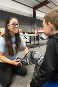 Share the Spirit Foundation Executive Director Jessica Page chats with a boy while fitting him for new shoes.