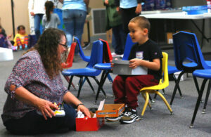 Volunteer Linda Jerome helps a little boy choose which shoes he wants to take home.
